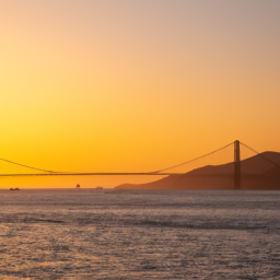 The Golden Gate Bridge at sunset, with an orange sky and calm waters.